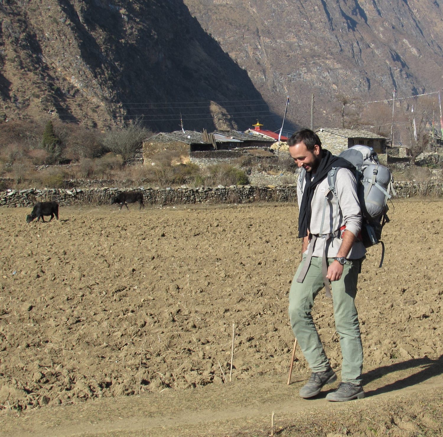 Bhuwan Tiwari walking the trail past a stone village in the Nepal Himalaya